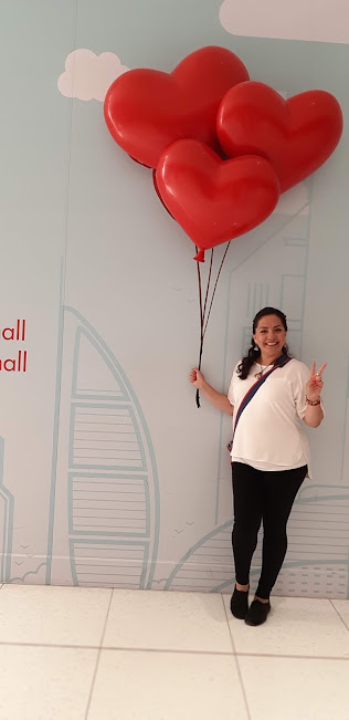Ilia García sosteniendo globos rojos en forma de corazón
